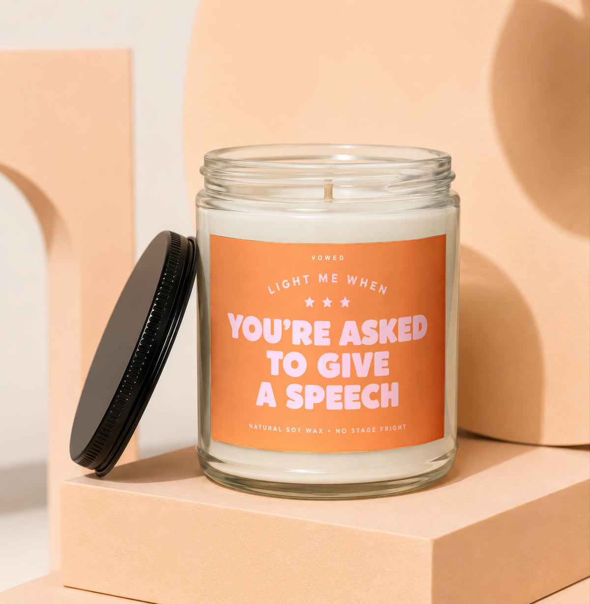 Glass jar candle with orange label reading "Light Me When You're Asked to Give a Speech".