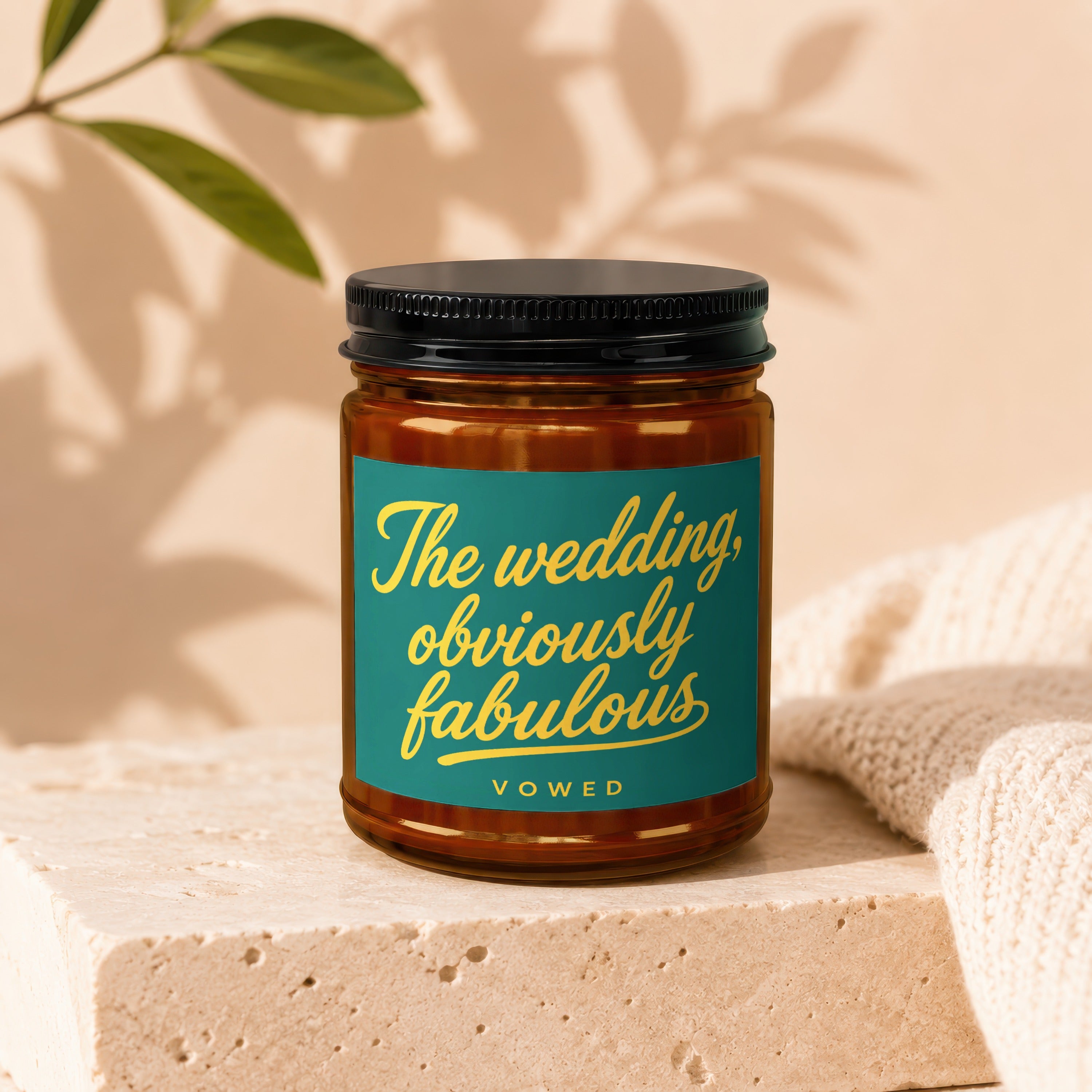 Amber jar candle with dark lid, teal label reads "The wedding, obviously fabulous."