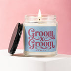 Candle with "Groom x Groom Vowed" text on blue label with a lit wick.
