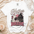 White t-shirt with "Mother of the Bride" text and a ghost bride near a haunted house.