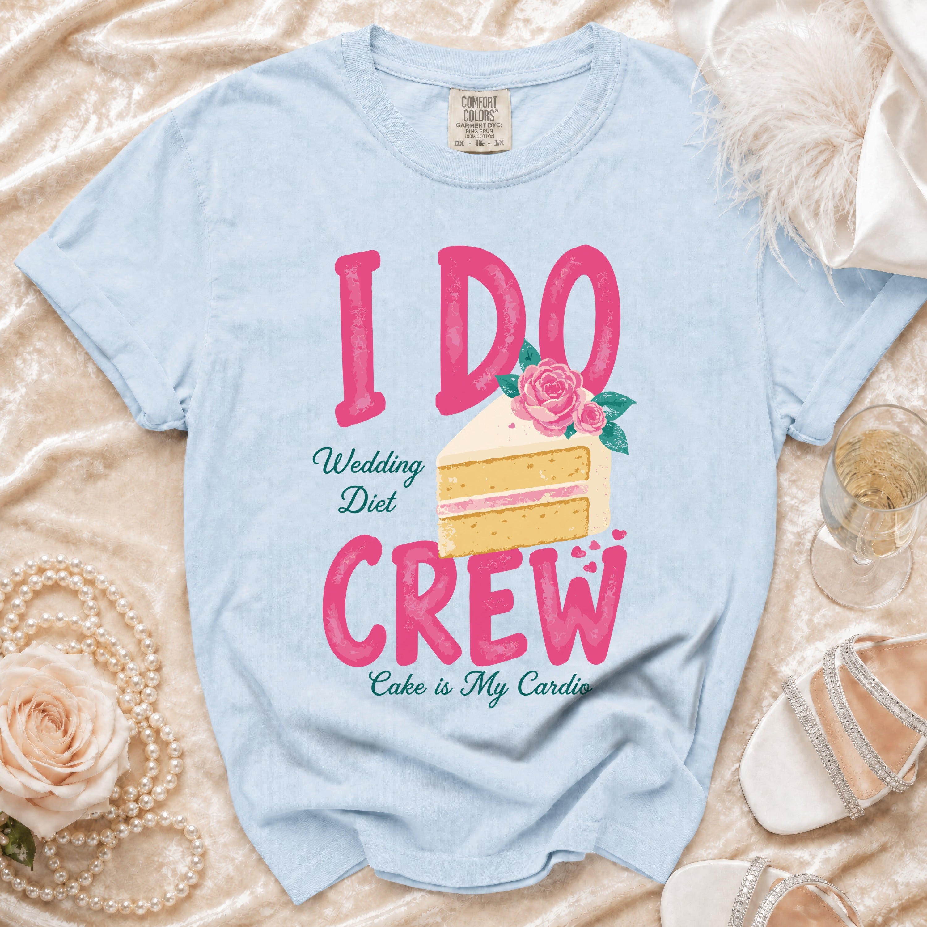 Light blue t-shirt with bold pink "I DO CREW" text and a slice of wedding cake.
