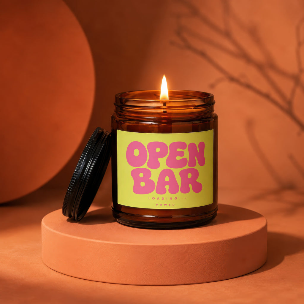Lit candle in amber jar with bright lime green label reading "OPEN BARLOADING... VOWED".