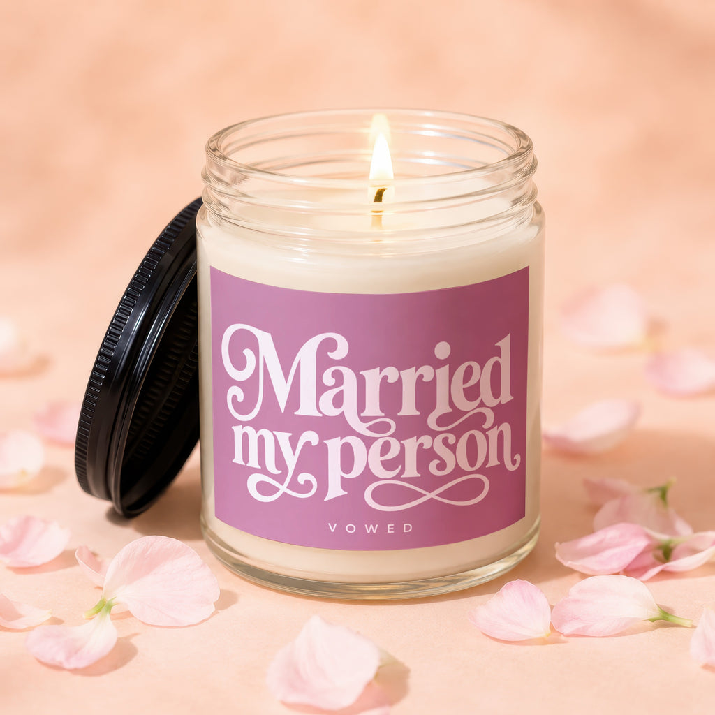 Jar candle with lit flame and "Married my person VOWED" text on pink label.