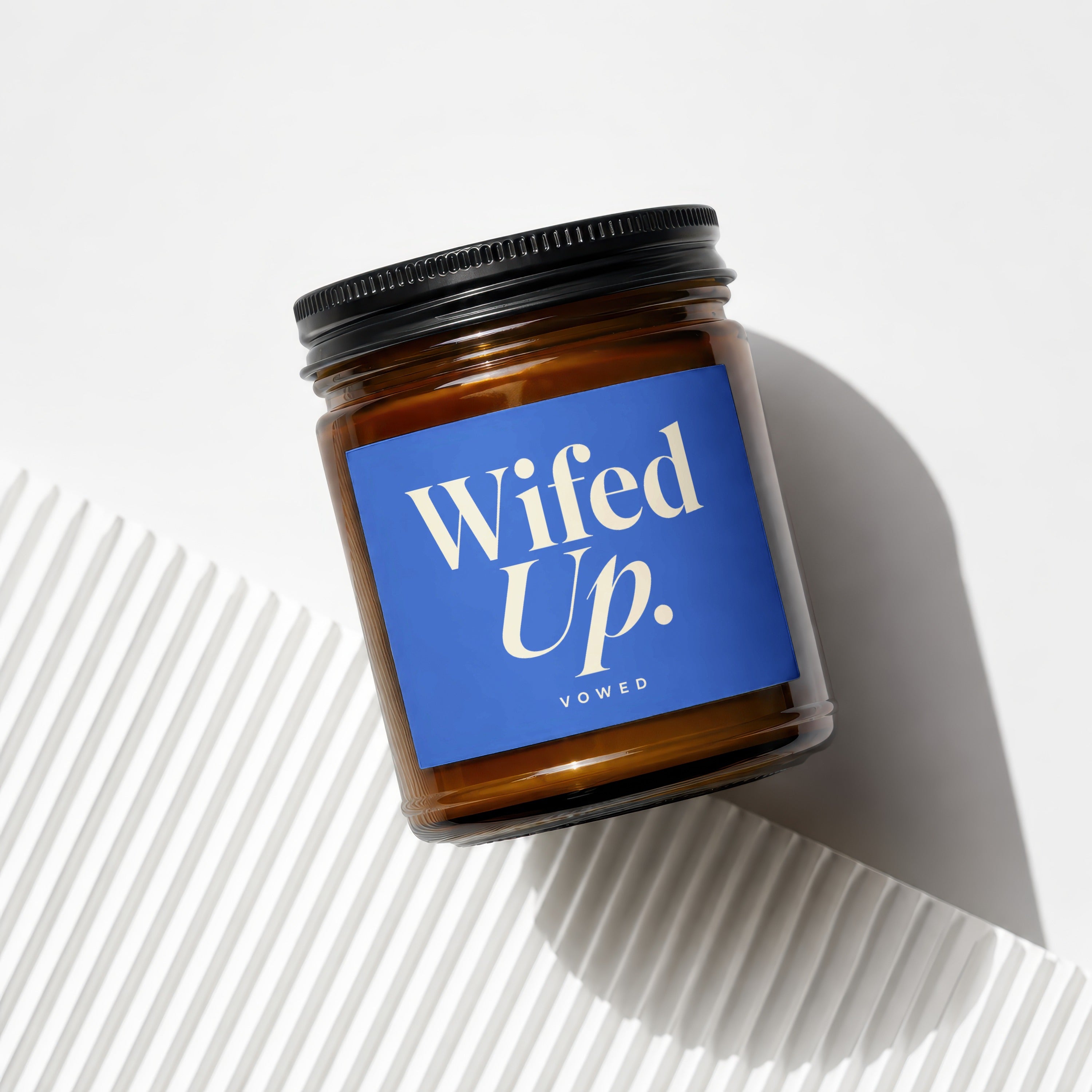 Amber jar candle with blue label reading "Wifed Up. VOWED".
