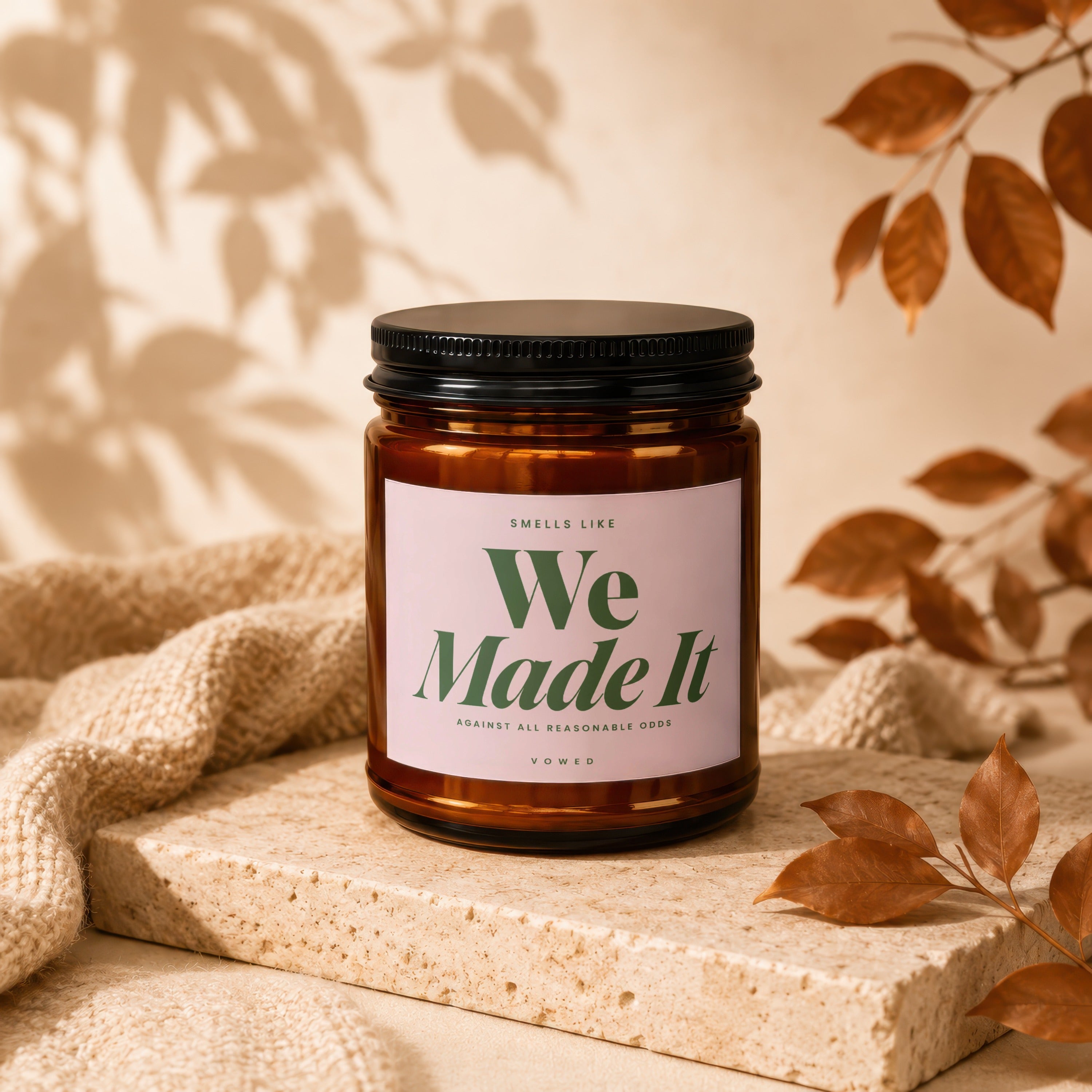 Amber jar candle with pink label reading "We Made It" and "Vowed".