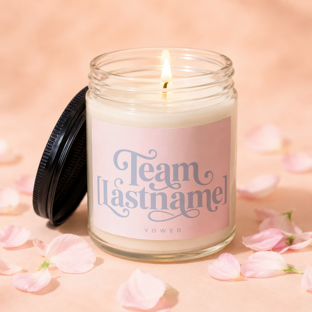 Lit candle in a jar with a pink label reading "Team Lastname" and "Vowed".
