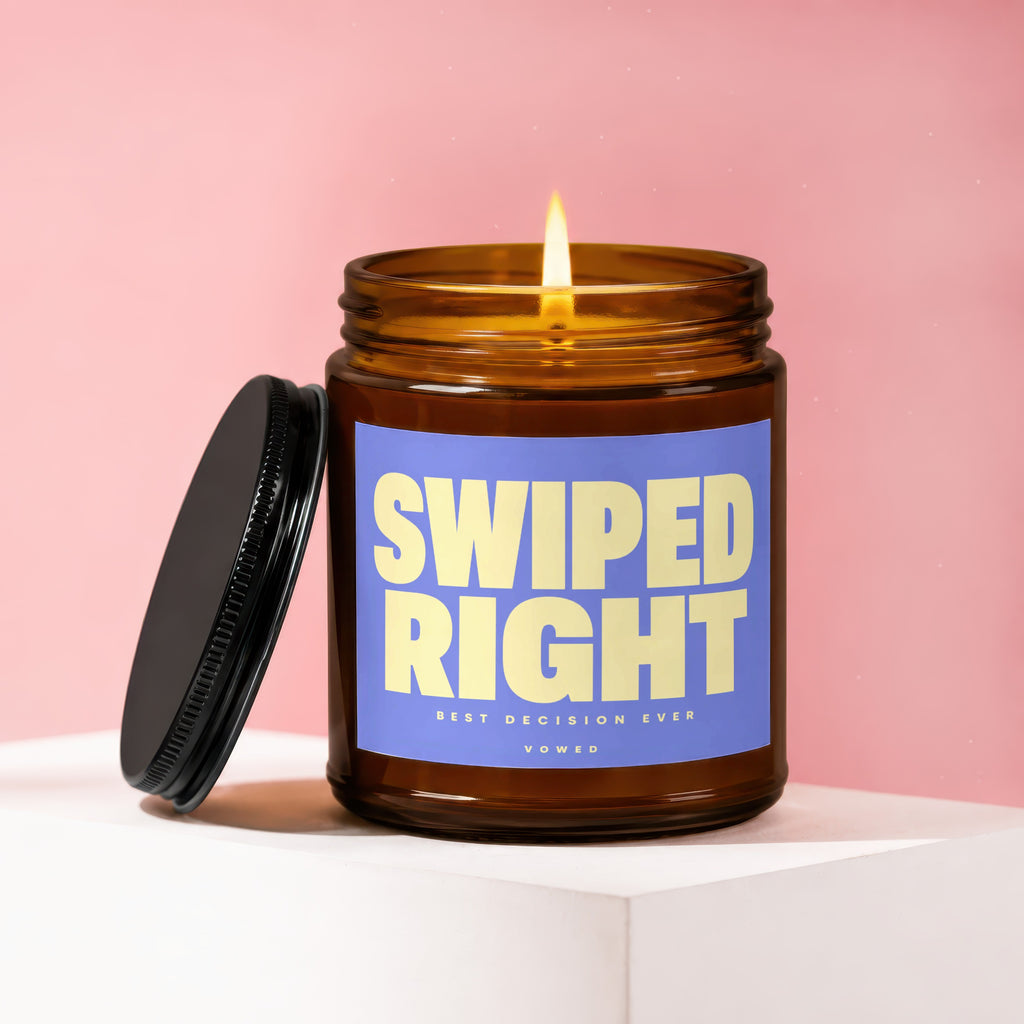 Amber jar candle with burning wick and blue label that reads "SWIPED RIGHT BEST DECISION EVER VOWED".