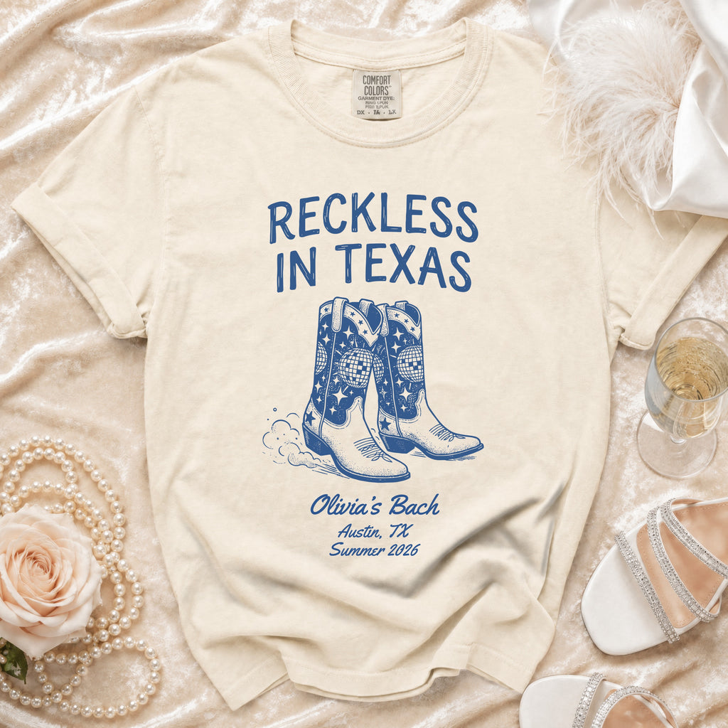 Cream t-shirt with "Reckless in Texas" and cowboy boots graphic, Olivia's Bach, Austin, TX, Summer 2026.