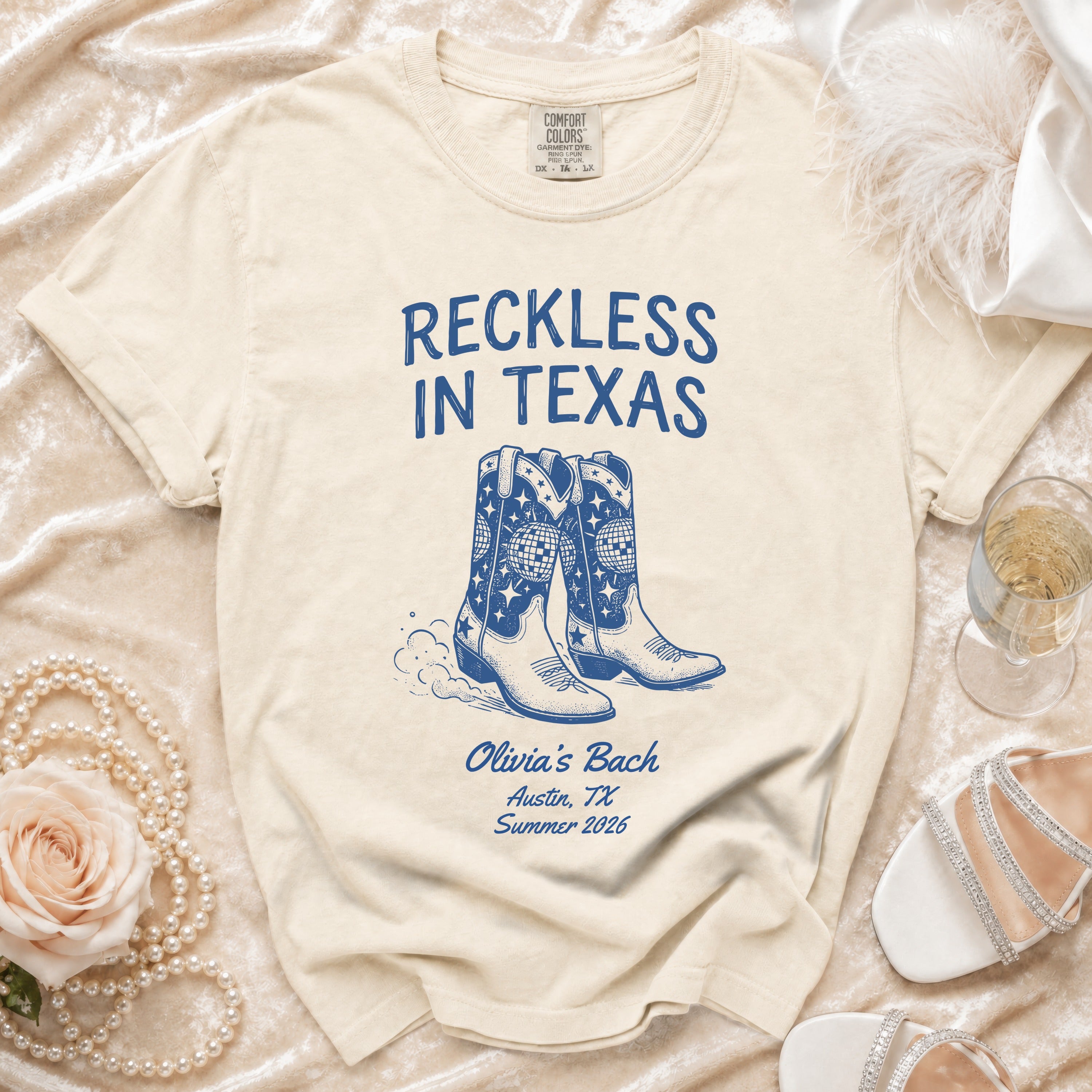 Cream t-shirt with "Reckless in Texas" and cowboy boots graphic, Olivia's Bach, Austin, TX, Summer 2026.