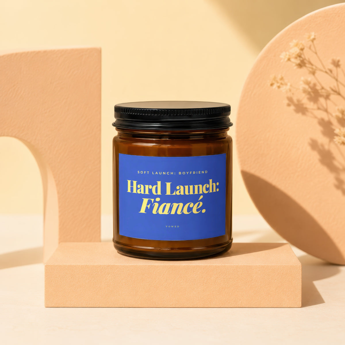 Amber jar candle with blue label reading "Hard Launch: Fiancé."