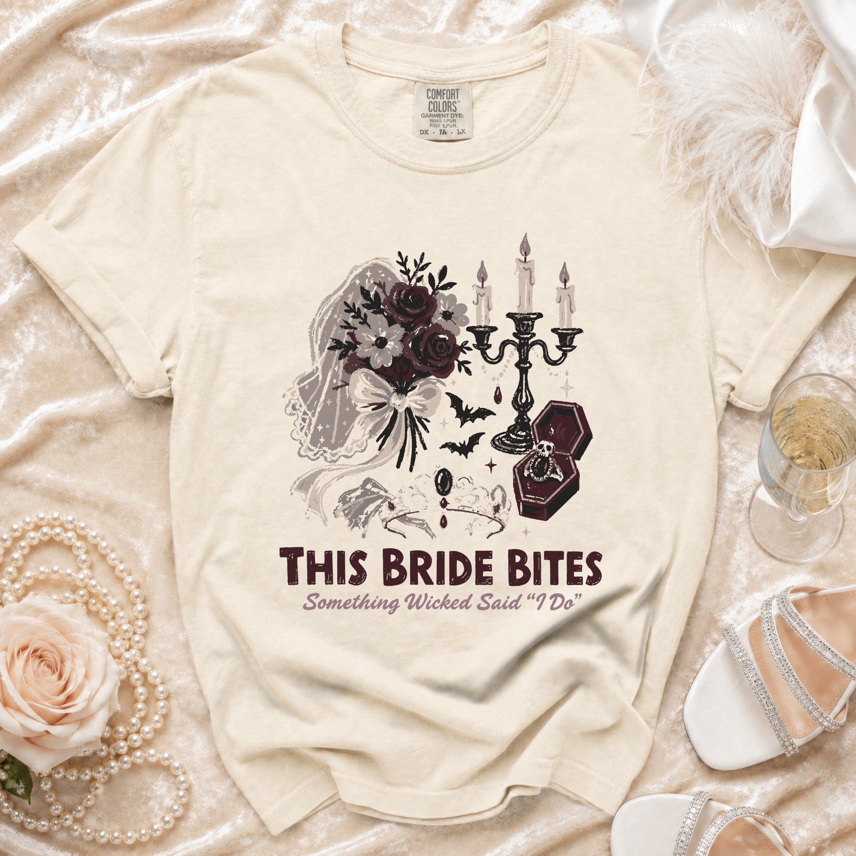 Cream t-shirt with graphic of bouquet, candelabra, coffin ring box, and text "THIS BRIDE BITES".