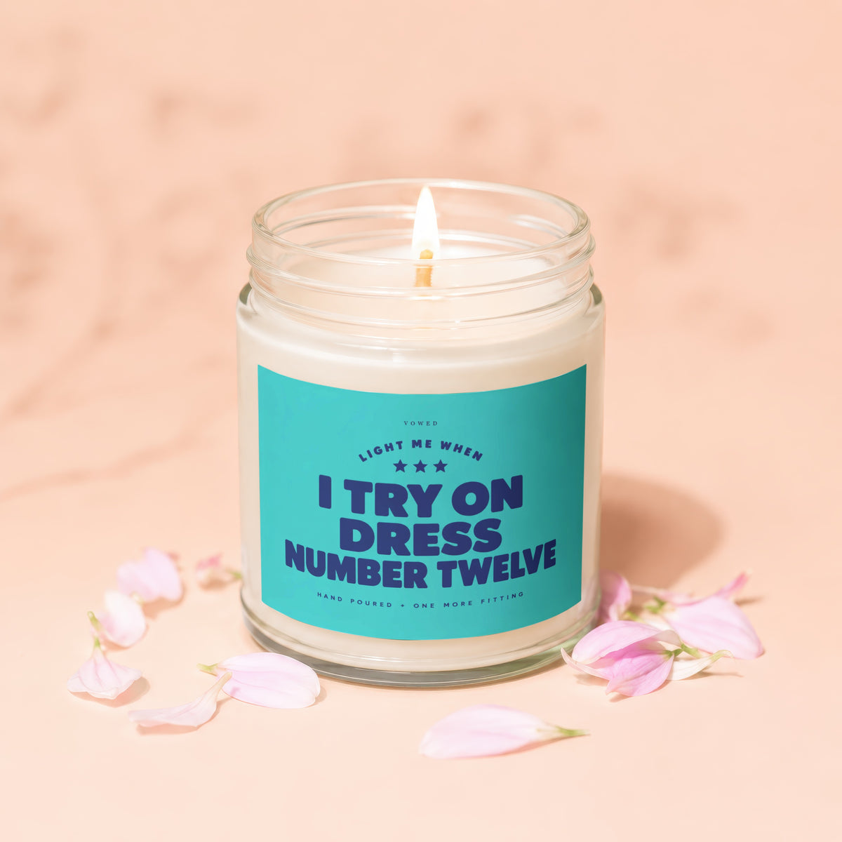 Candle with teal label reading "I TRY ON DRESS NUMBER TWELVE".