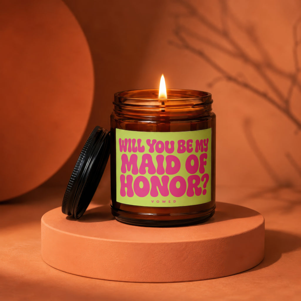 Amber jar candle with a lit wick and a label asking "Will you be my Maid of Honor?".