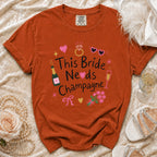 Orange t-shirt with "This Bride Needs Champagne" graphic and bridal accessories.