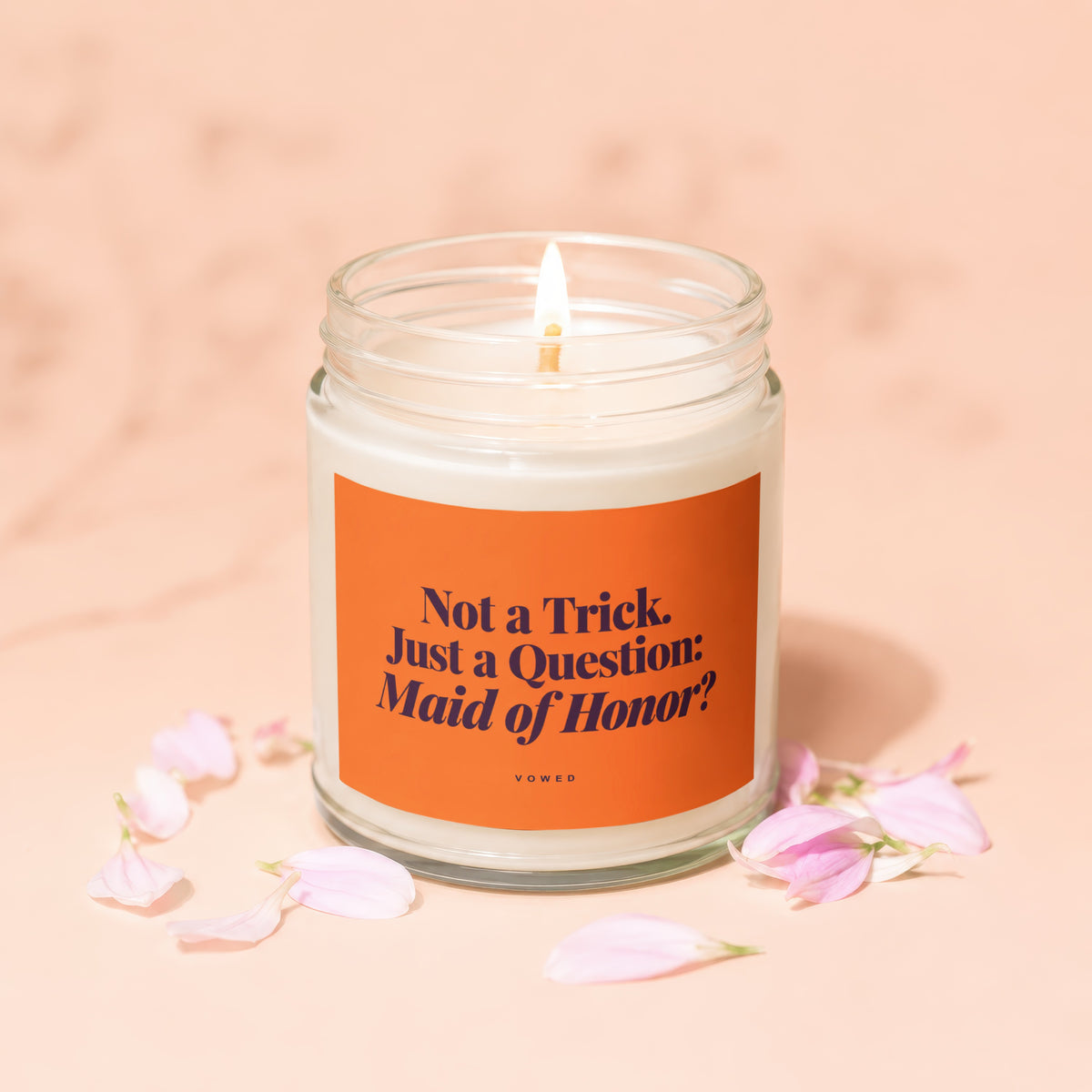 Candle with orange label that reads "Not a Trick. Just a Question: Maid of Honor?"