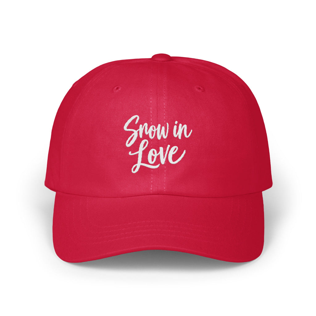 A solid red baseball cap featuring the white embroidered text Snow in Love on the front.