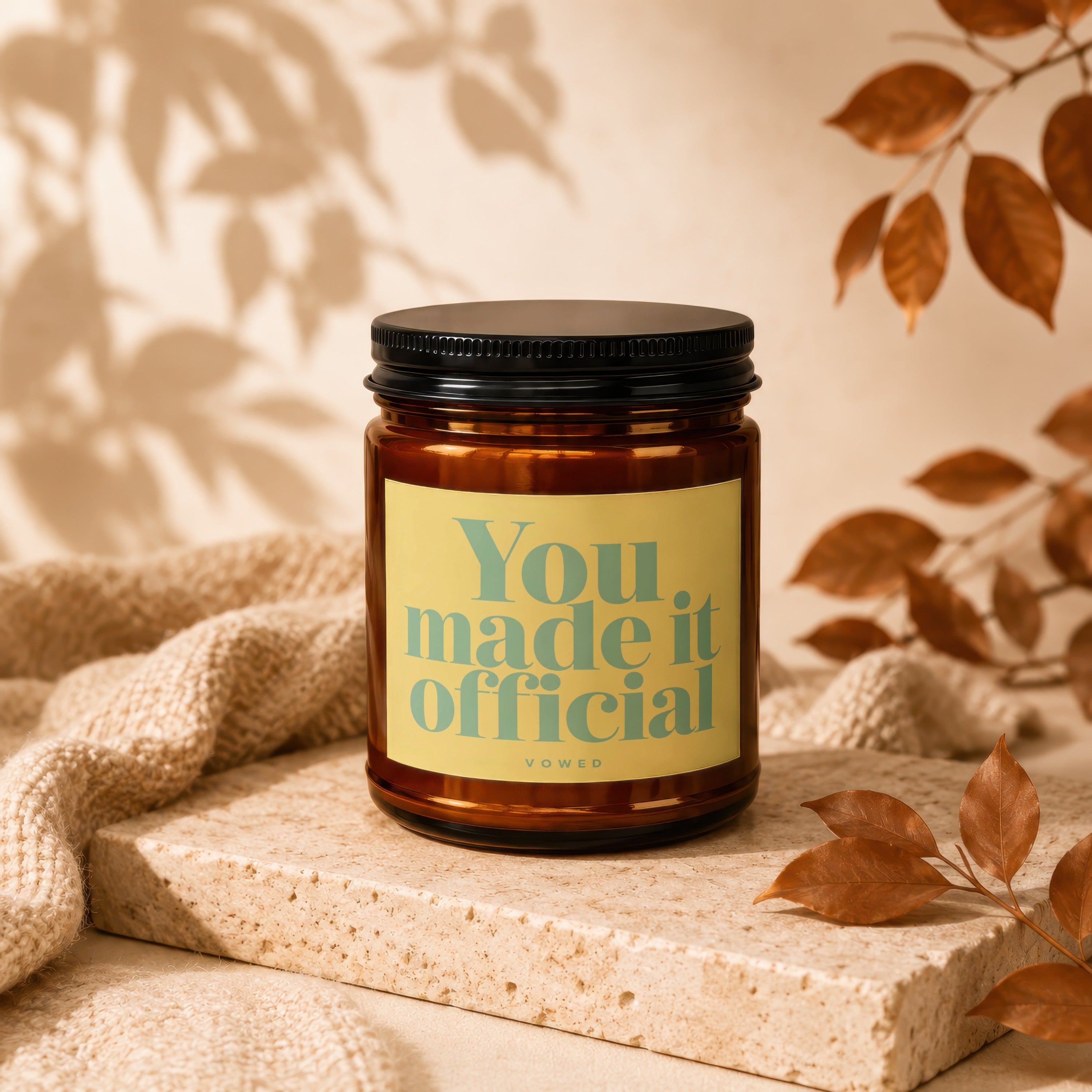 Amber candle in a jar with a black lid and "You made it official vowed" label.