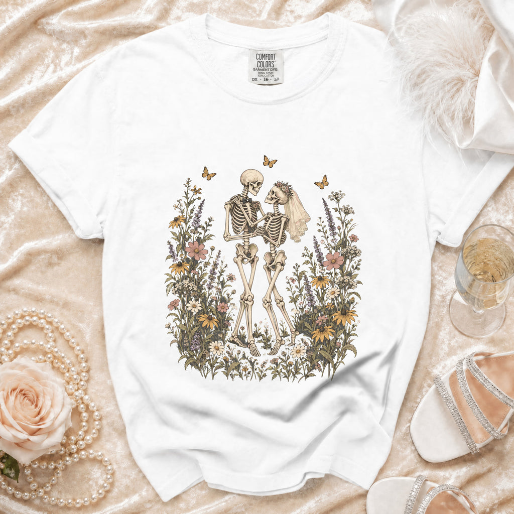 White t-shirt with a vintage-style print of skeletons in a floral garden.