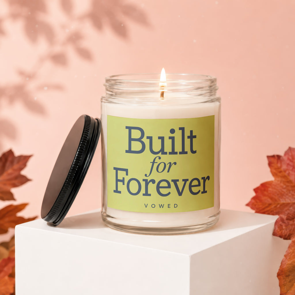 Glass jar candle with lid off, displaying "Built for Forever" text on a tan background with autumn leaves.