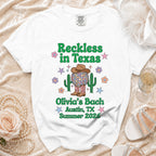 White t-shirt with "Reckless in Texas" and "Olivia's Bach Austin, TX Summer 2026" text.