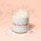 Glass candle with lit wick, label reads "Wife Era Pending".