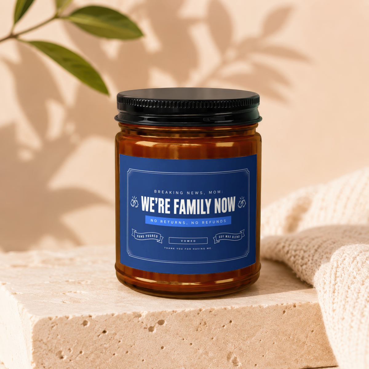 Amber jar candle with a blue label reading "We're Family Now" with wedding rings.