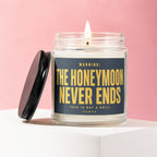 Glass candle with lit wick and black lid, reads "WARNING: THE HONEYMOON NEVER ENDS THIS IS NOT A DRILL VOWED"