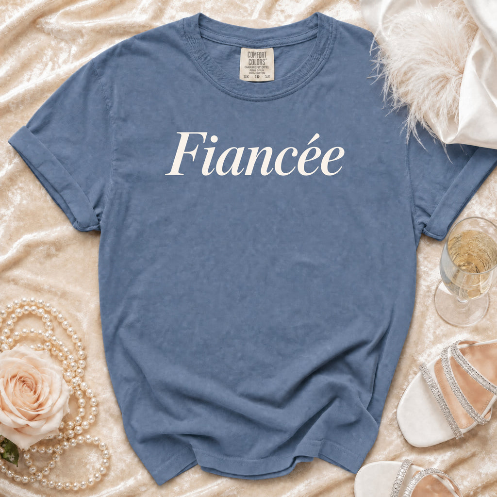 Blue t-shirt with "Fiancée" printed in white, displayed with wedding accessories.