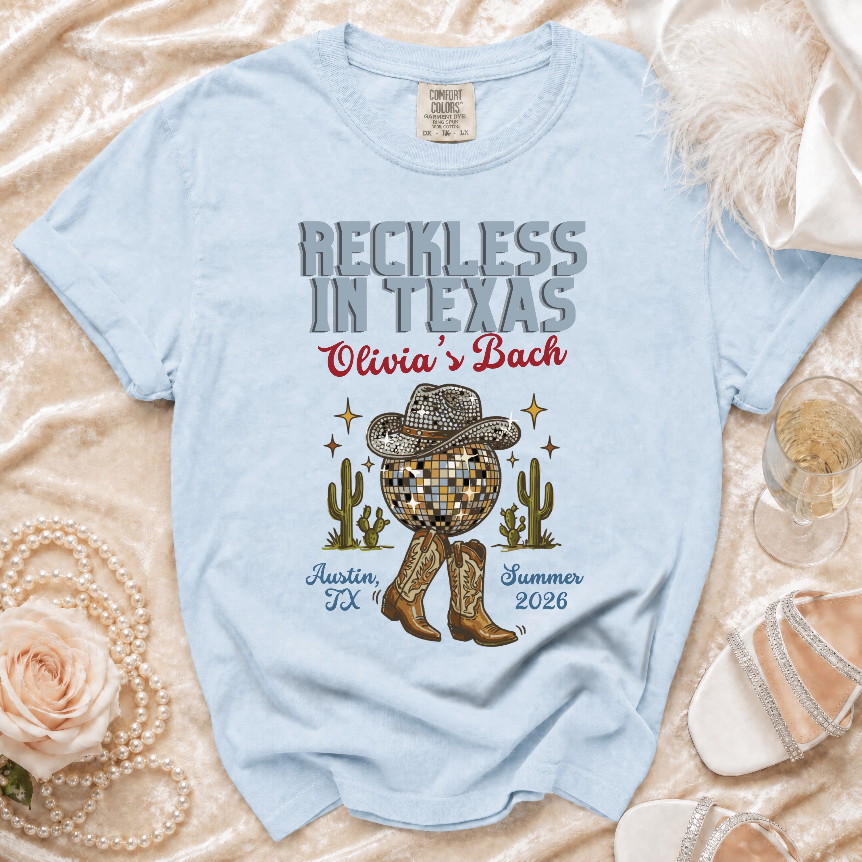 Light blue t-shirt with "Reckless in Texas Olivia's Bach" design.