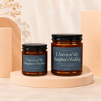 Two glass candles with dark lids, labeled "I Survived My Daughter's Wedding."