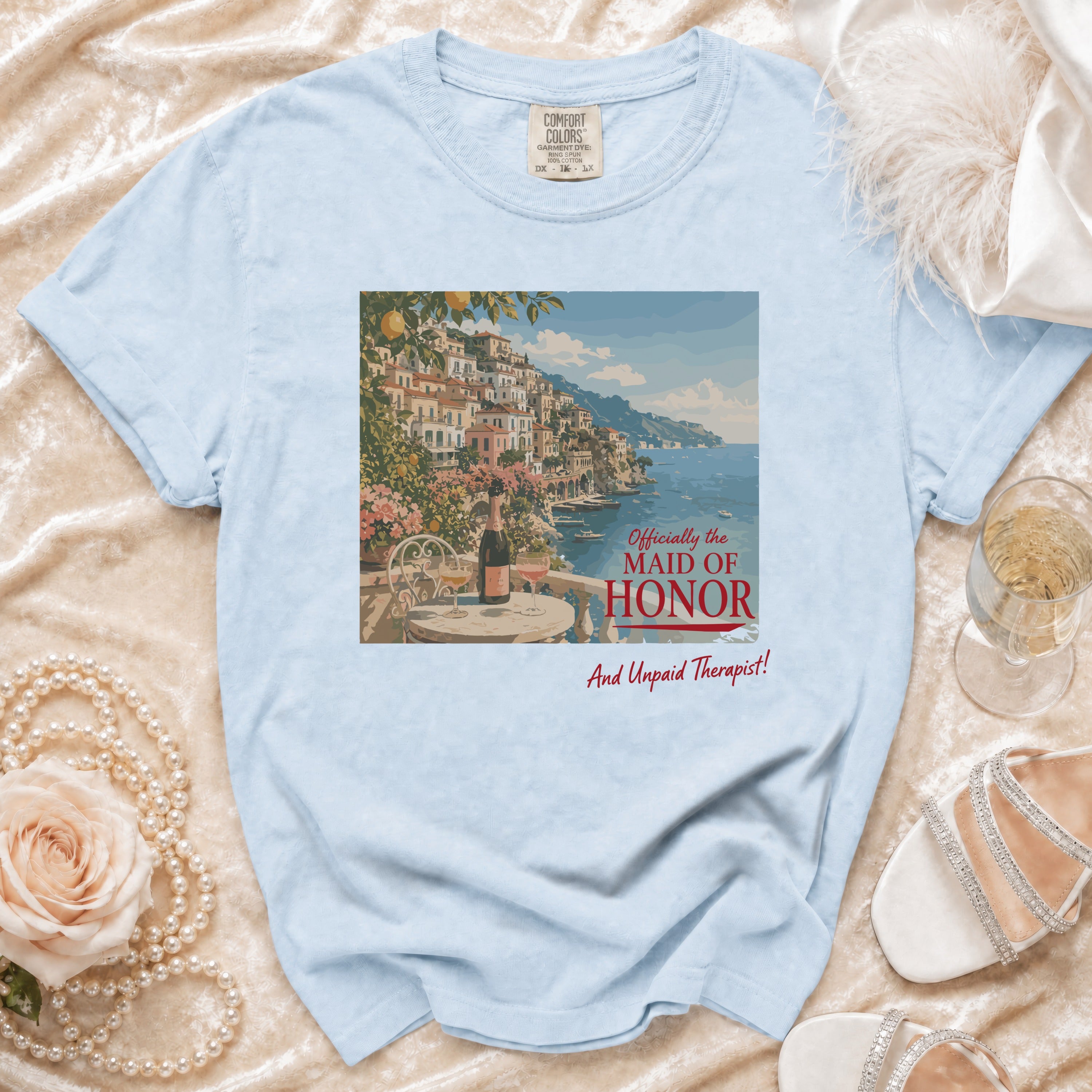 Light blue t-shirt with village scene and text "Officially the Maid of Honor And Unpaid Therapist!"