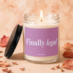 Glass candle with lit wick, purple label reading "Finally legal" and "VOWED".