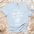 Light blue t-shirt with "Olivia's Bach Reckless in Texas Austin TX Summer 2026" text.
