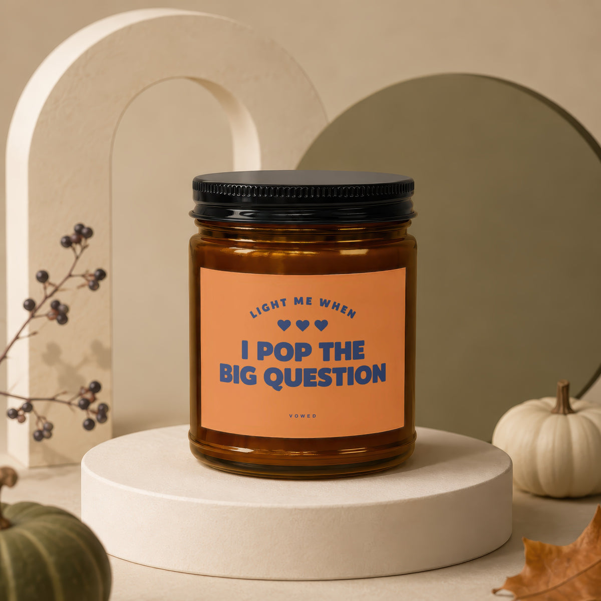 Brown glass candle with orange label reading "Light me when I pop the big question."