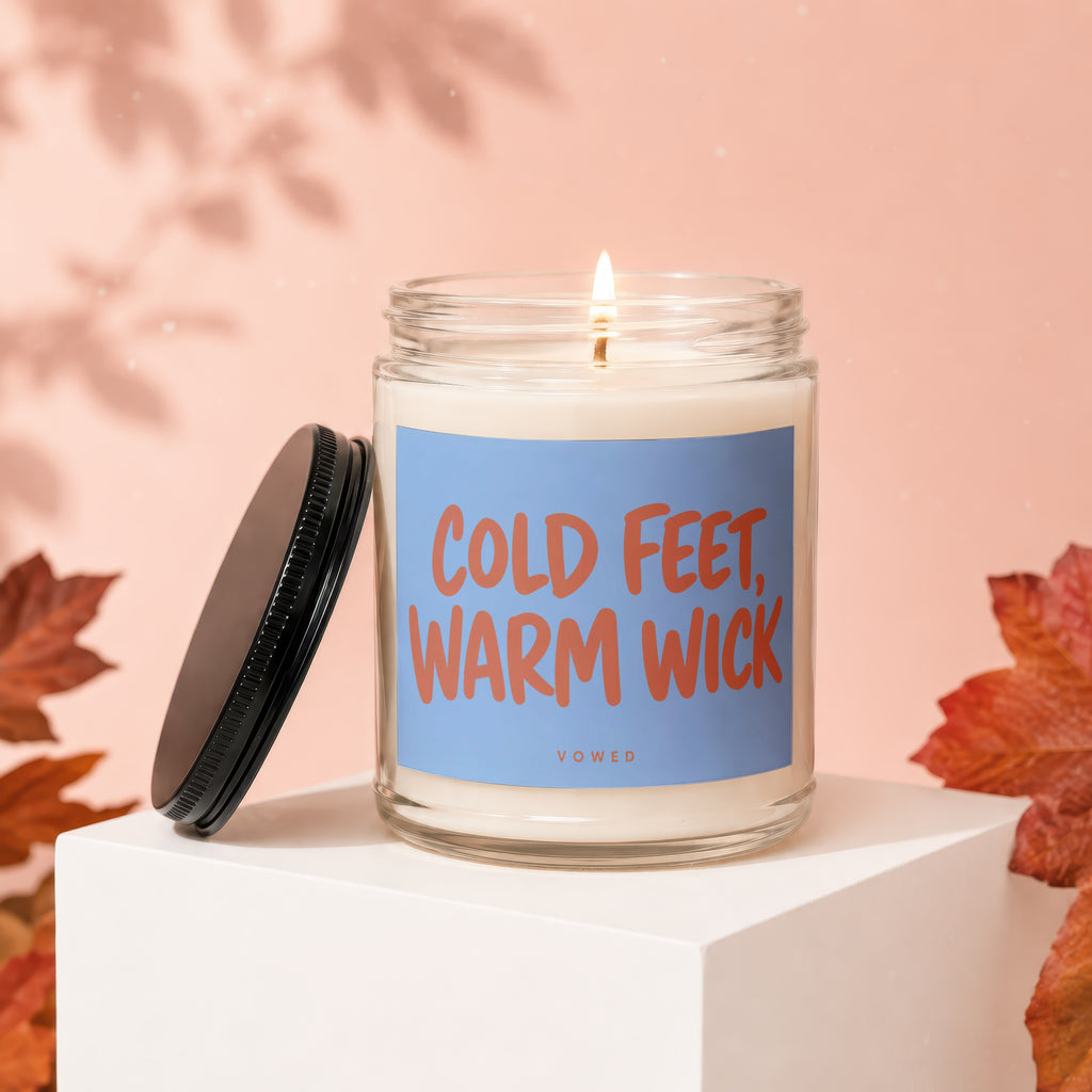Glass candle with "Cold Feet, Warm Wick" text on a light blue label.