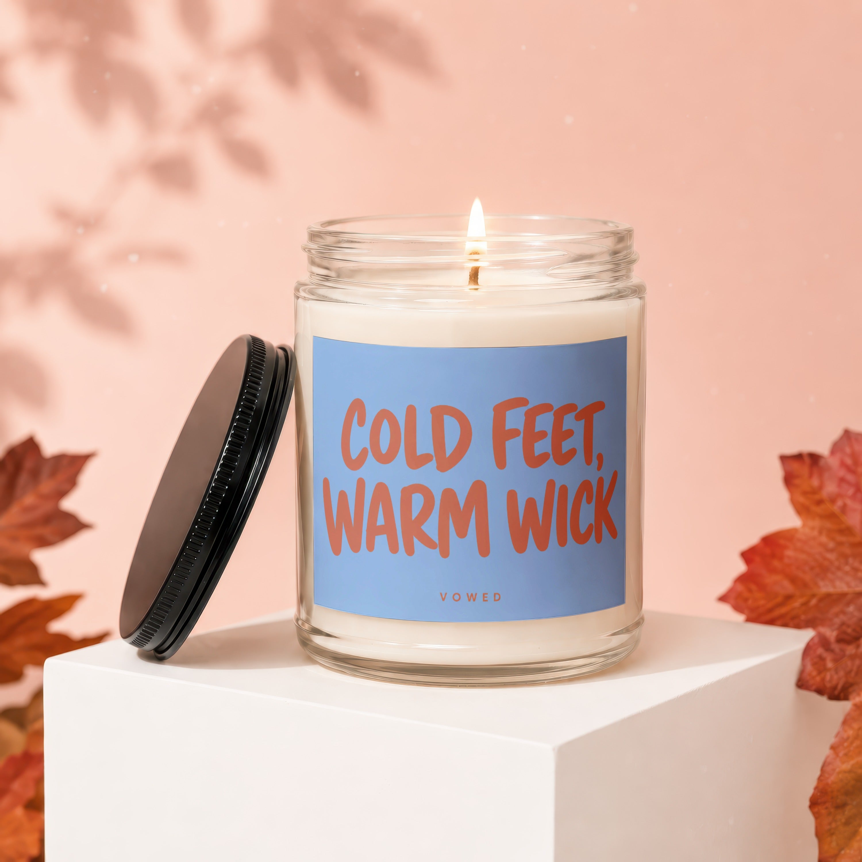 Glass candle with "Cold Feet, Warm Wick" text on a light blue label.