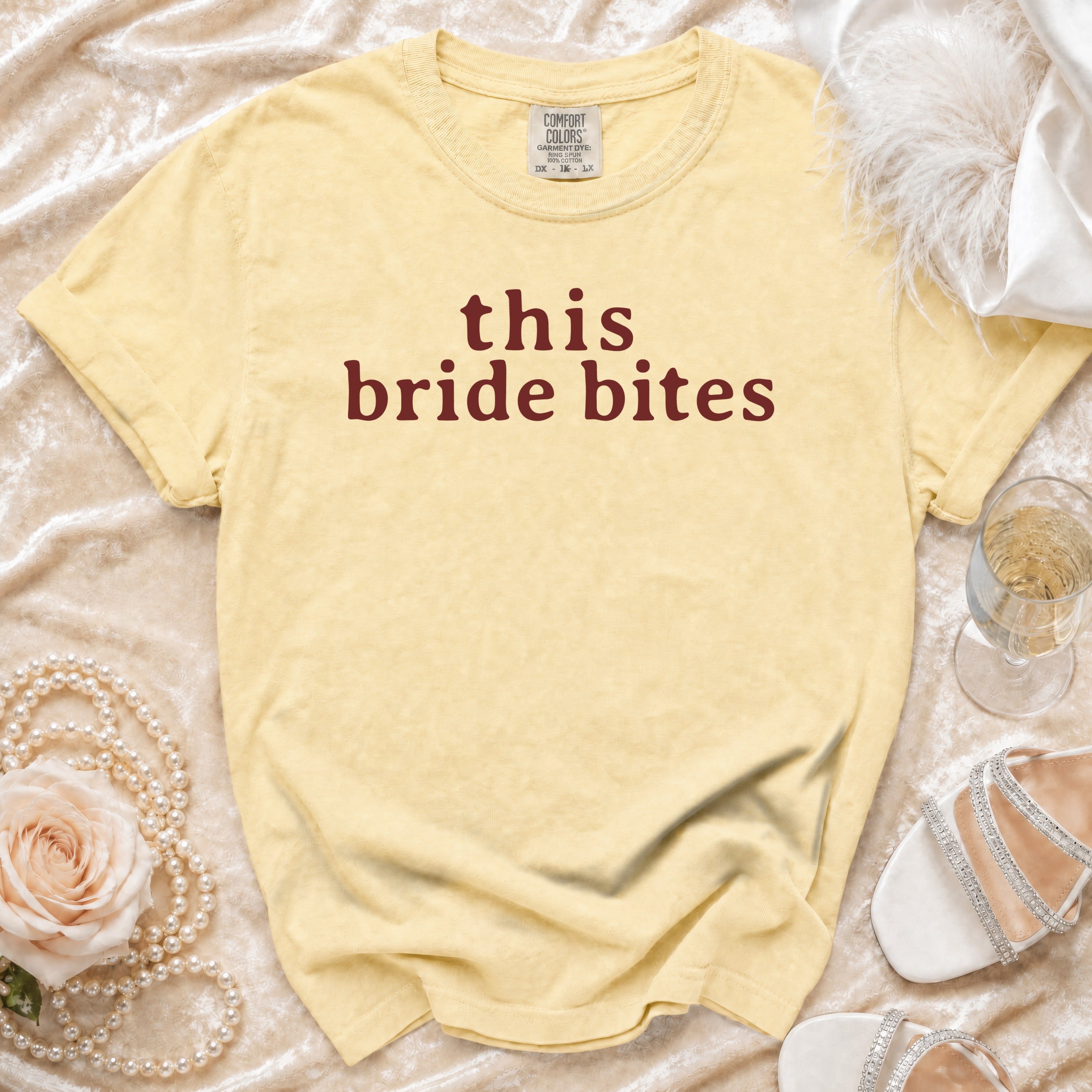 Yellow t-shirt with "this bride bites" text, pearls, rose, and shoes.