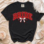 Black t-shirt with red "BRIDE" text, white bow, and sparkles.