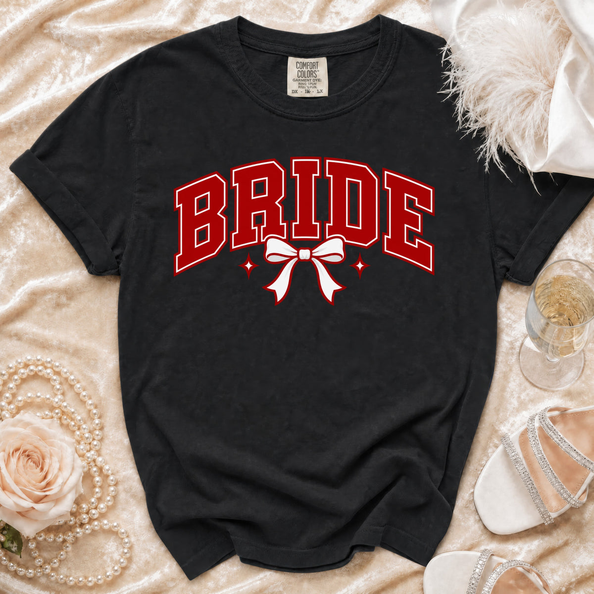Black t-shirt with red "BRIDE" text, white bow, and sparkles.