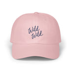 A light pink baseball cap features embroidered blue text reading Wild Wild on the front.