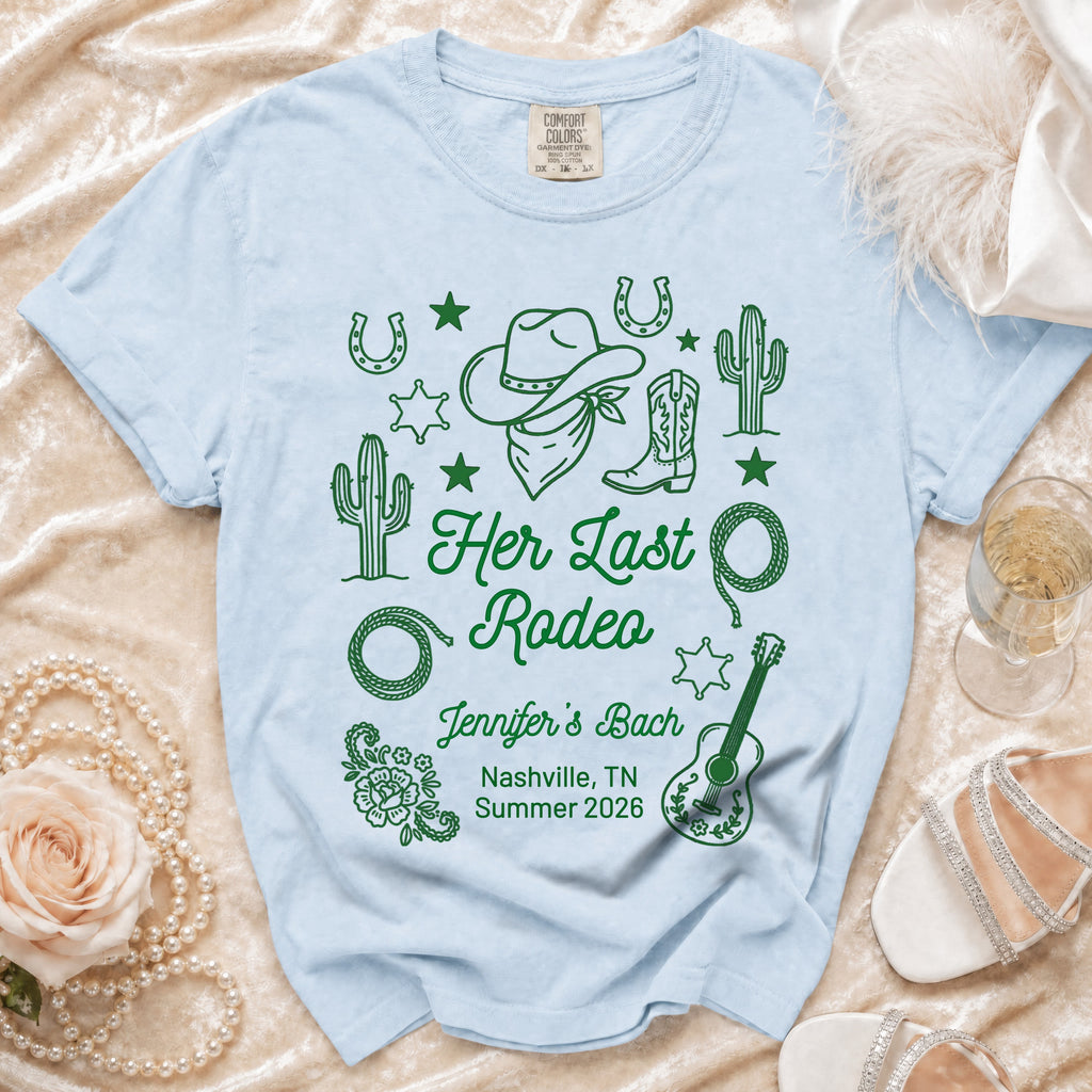 Light blue Comfort Colors t-shirt with "Her Last Rodeo" and event details in green.