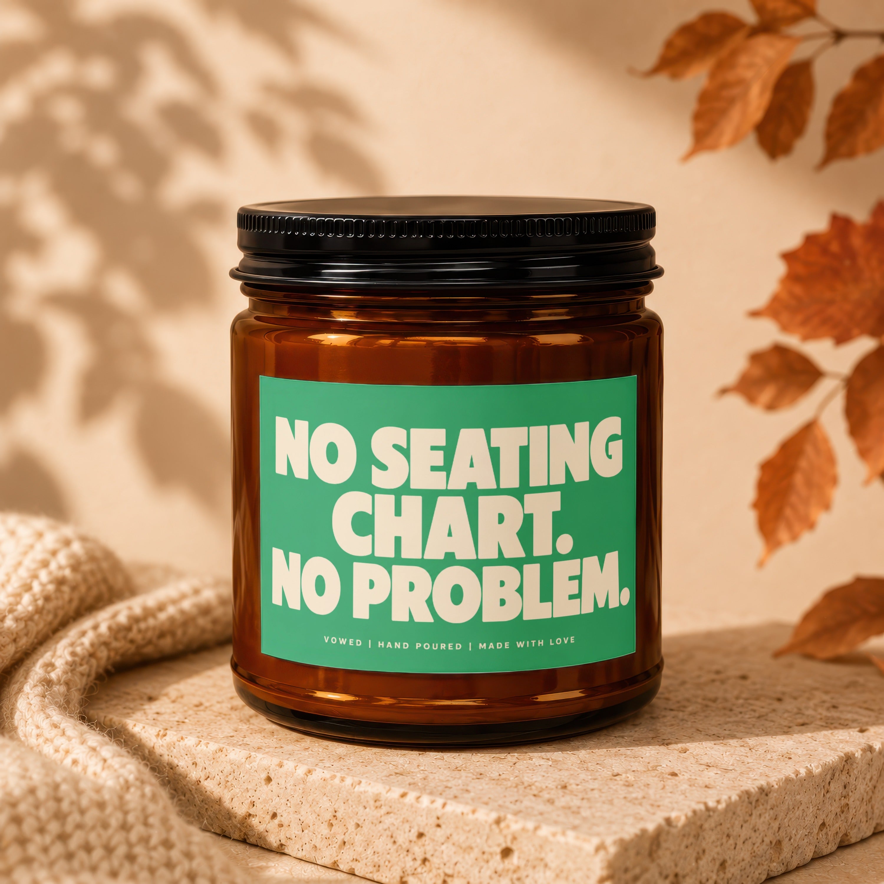 Amber jar candle with "No seating chart. No problem." text on green label.
