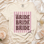 Cream t-shirt with "BRIDE to be BRIDE" text and a bow design.