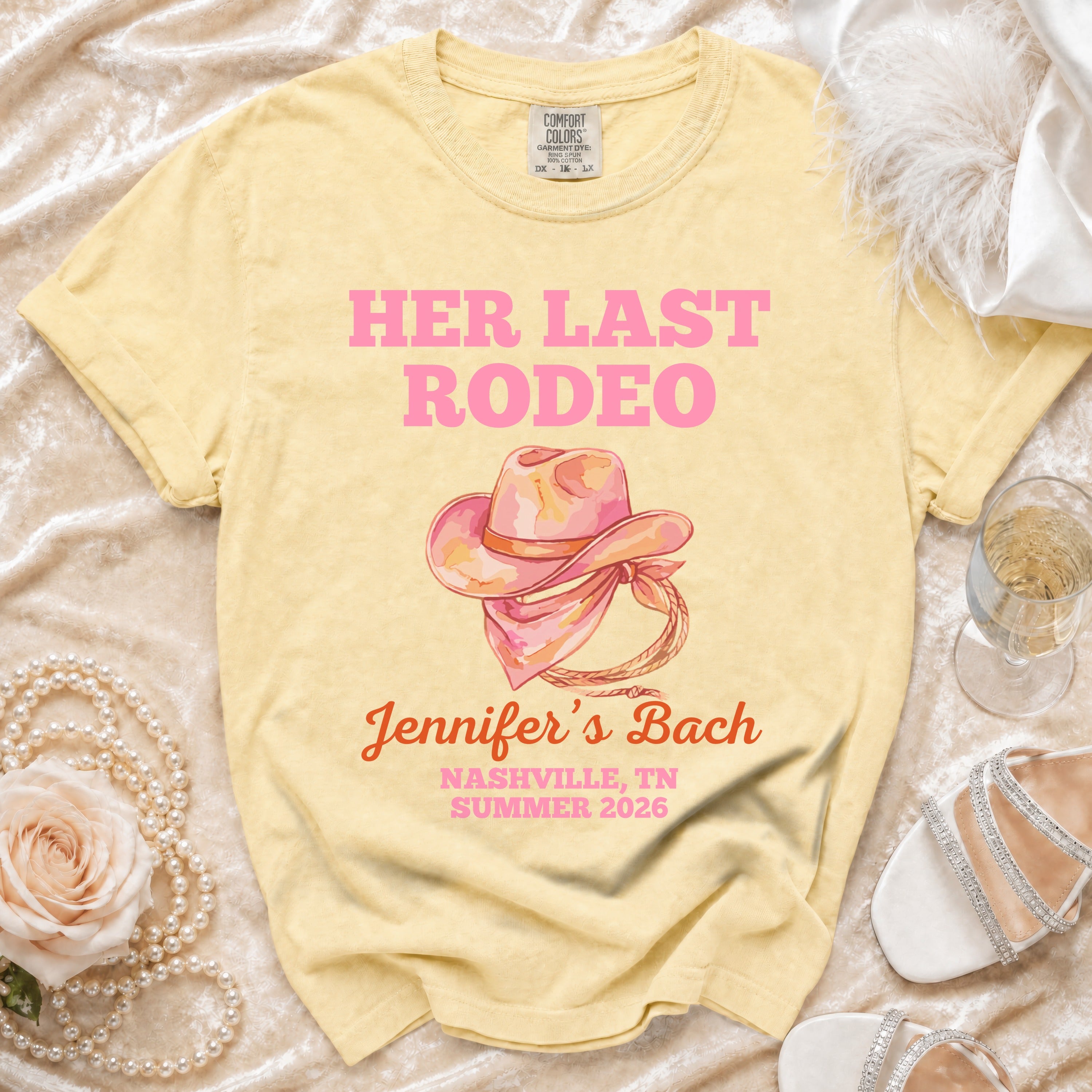 Pink watercolor cowboy hat graphic on a yellow t-shirt with event details.