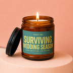 Amber jar candle with lit flame and "Surviving Wedding Season" text.
