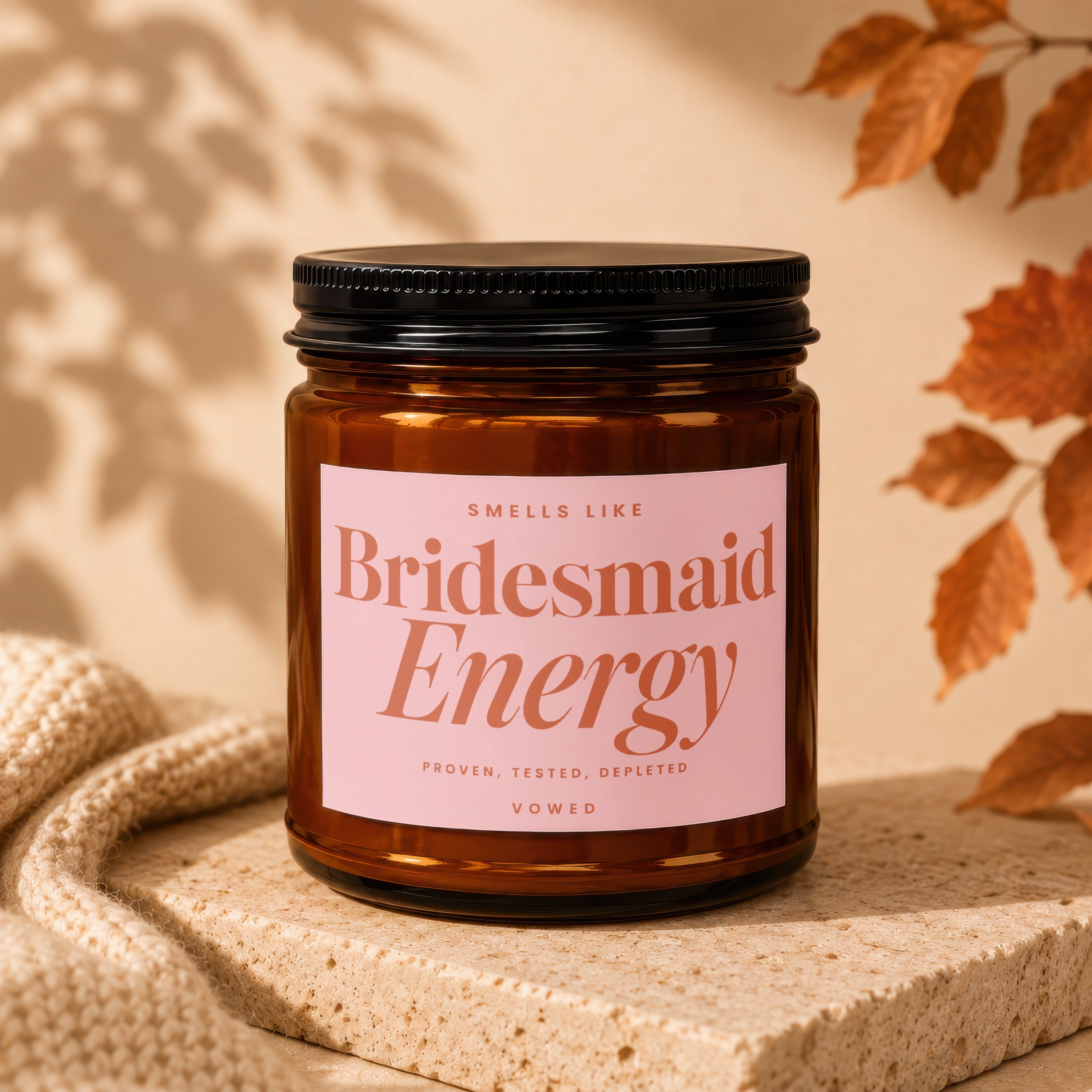 Amber candle with pink label reading "Smells like Bridesmaid Energy Proven, Tested, Depleted VOWED".