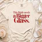 Cream t-shirt with red text reading "This Bride needs a Bigger Glass".