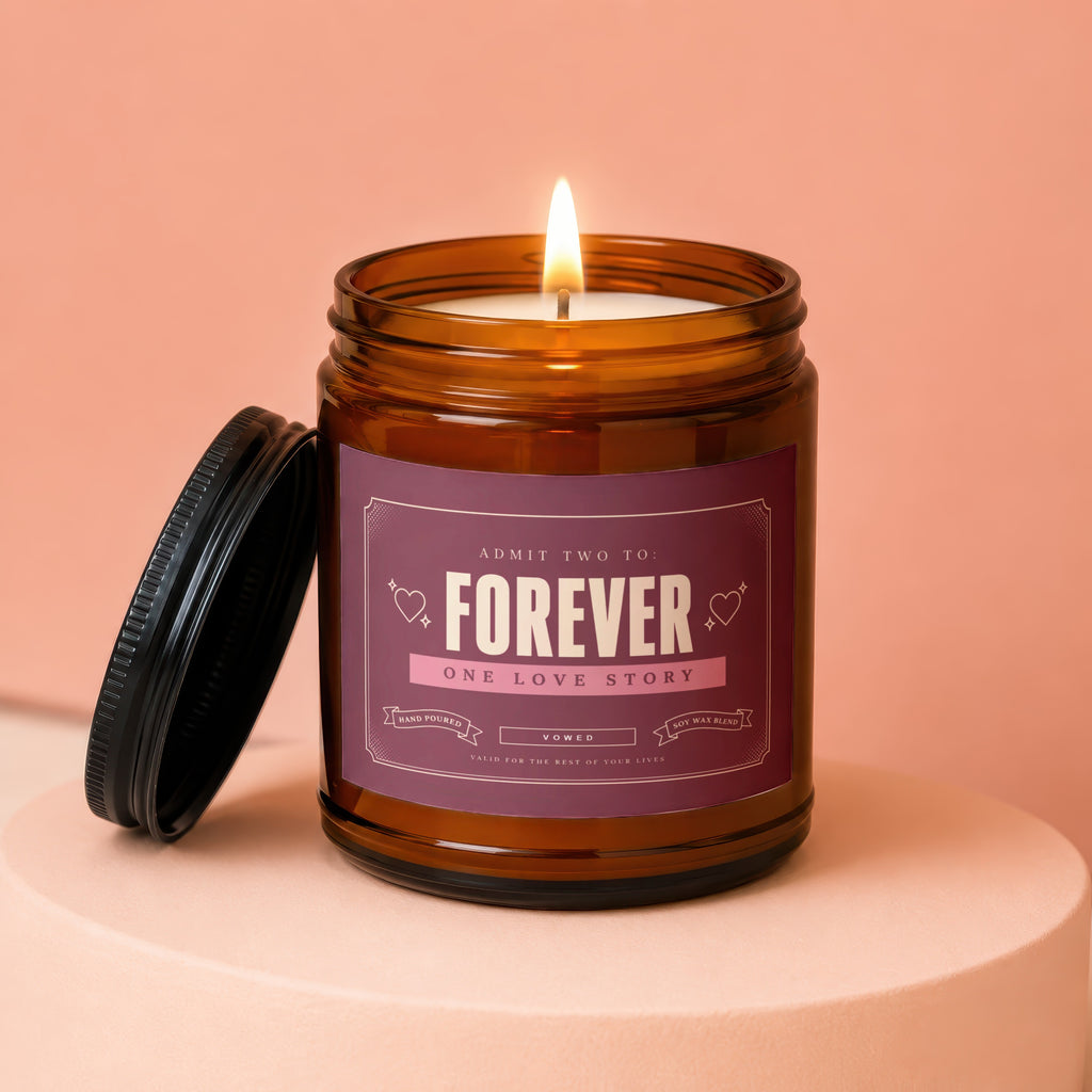 Amber candle with "Forever One Love Story" label, lid off, lit flame.