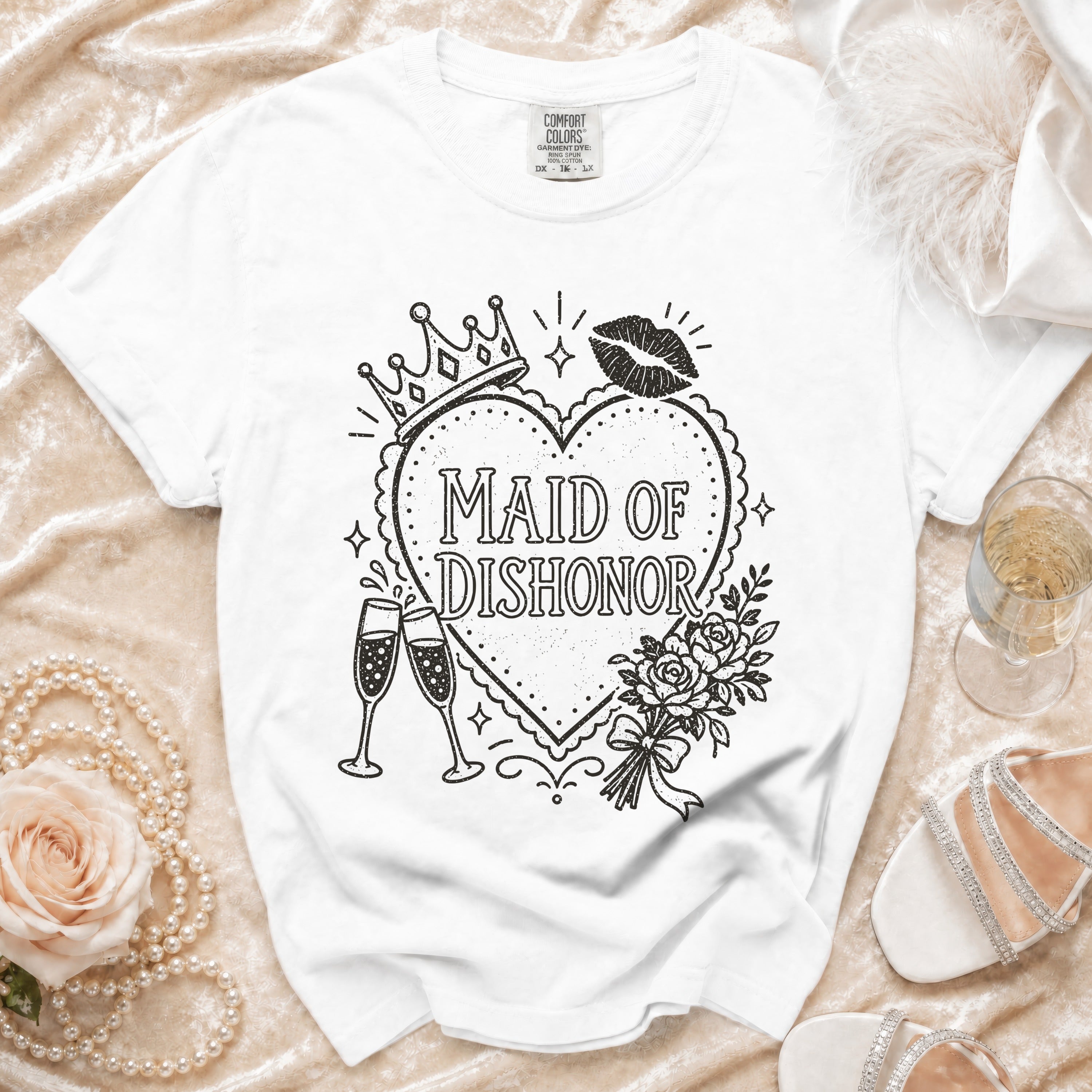 White t-shirt with "Maid of Dishonor" text, crowns, lips, roses, and champagne glasses.