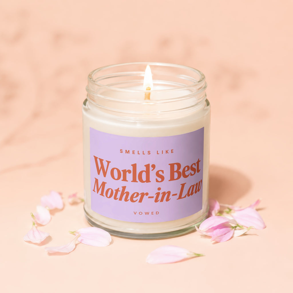Glass jar candle with lit wick, purple label reads "World's Best Mother-in-Law".